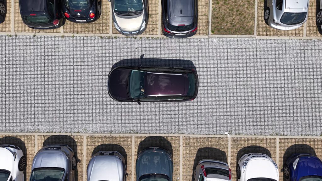 samochód jadący po drodze z ekokraty między miejscami parkingowymi